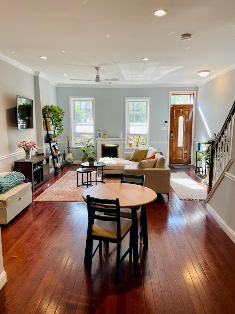 Elegant living room in a Philadelphia residence featuring polished hardwood flooring with a deep mahogany sheen, complemented by natural light, a cozy seating arrangement, and a welcoming entrance. This image captures the second phase of a hardwood floor refinishing project, highlighting the floor's enhanced beauty and durability.